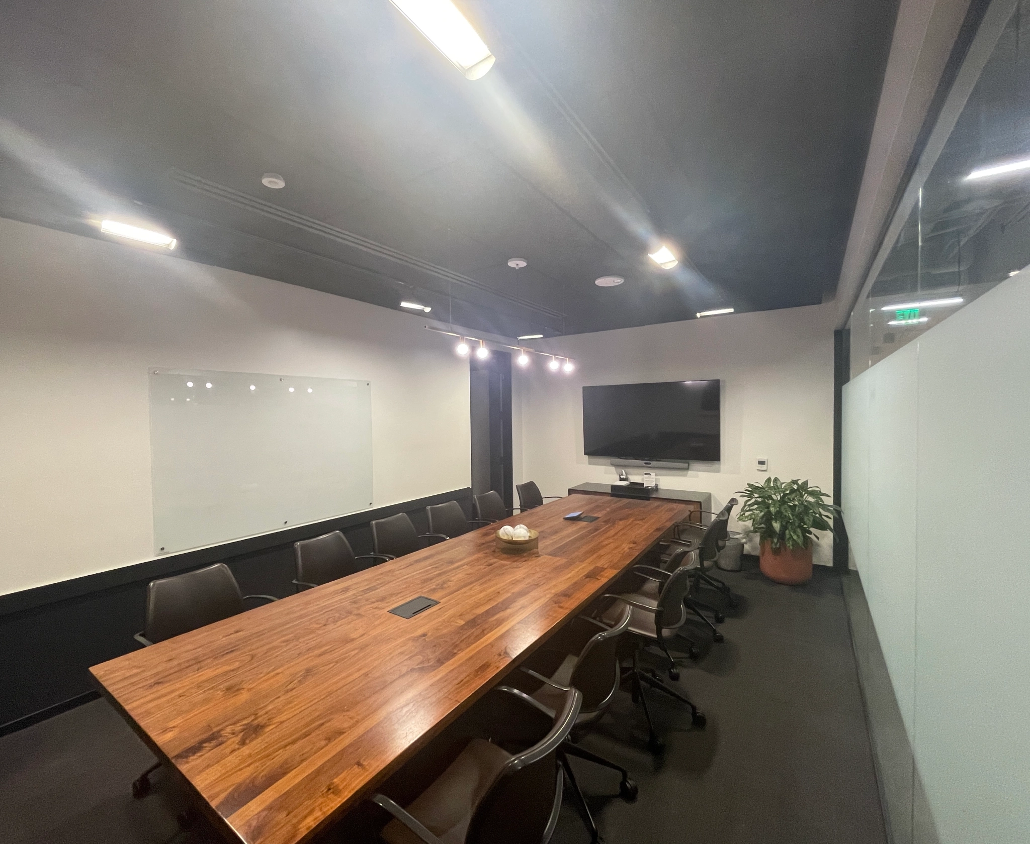 A coworking space featuring a conference room with a wooden table and chairs.