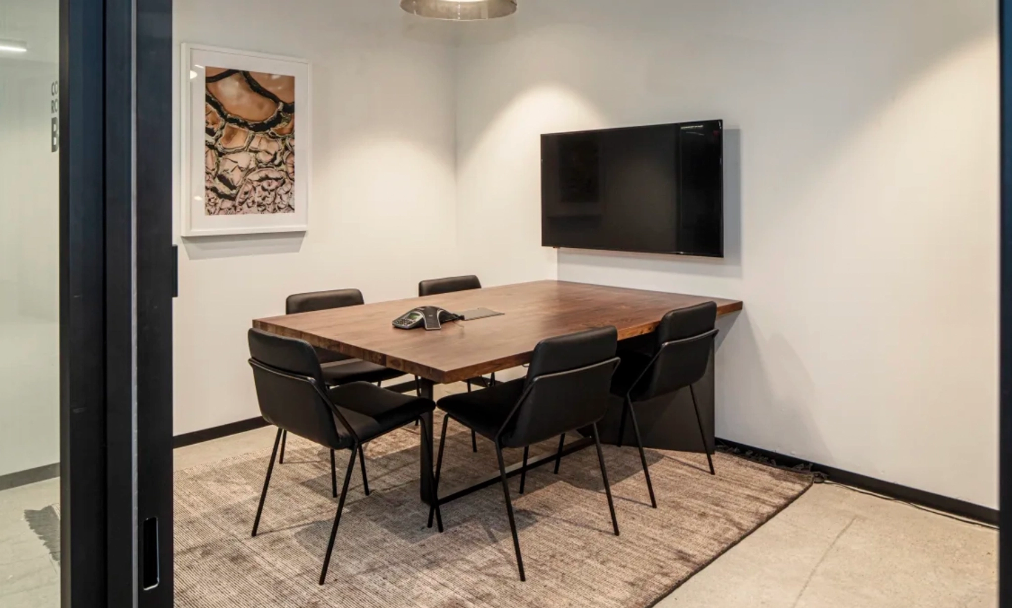 A coworking space with a conference room equipped with a table and chairs, ideal for office meetings and collaborative workspace.