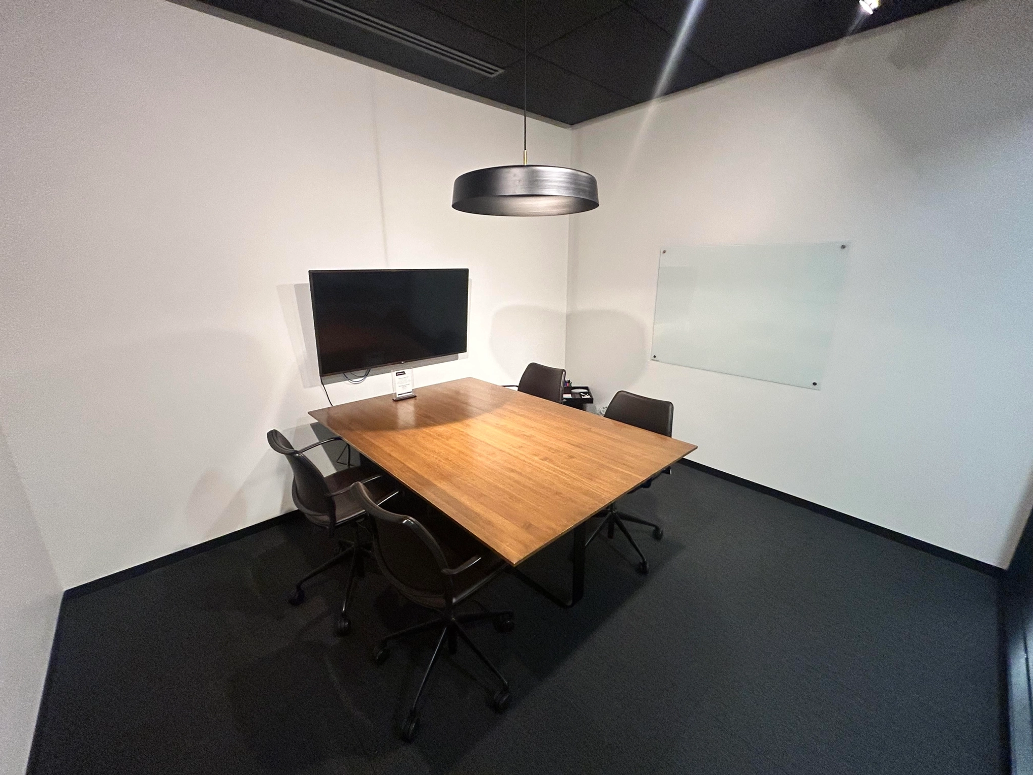 Une salle de réunion de coworking à Evanston, équipée d'une table, de chaises et d'une télévision.