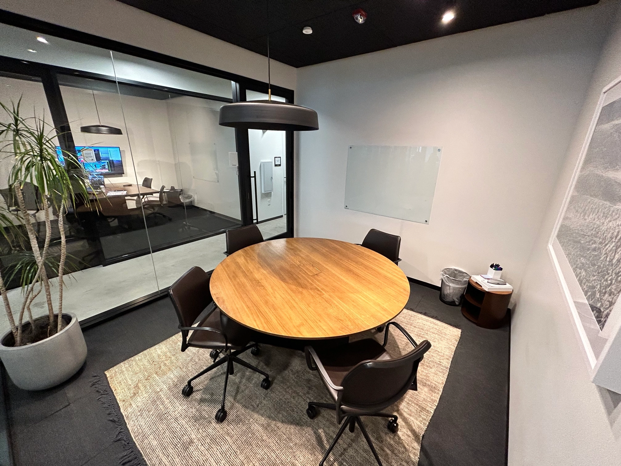 A coworking meeting room furnished with a wooden table and chairs.