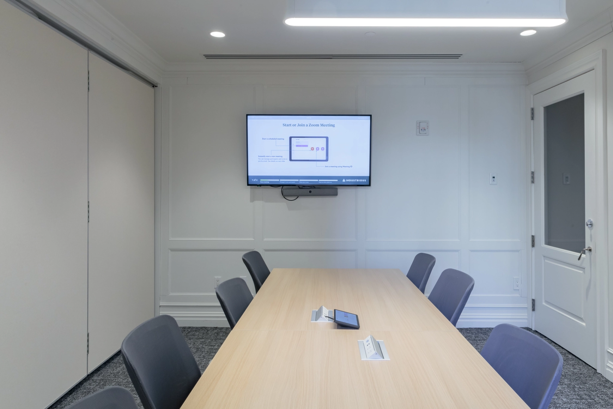 A workspace in New York that doubles as a conference room, featuring a TV mounted on the wall.