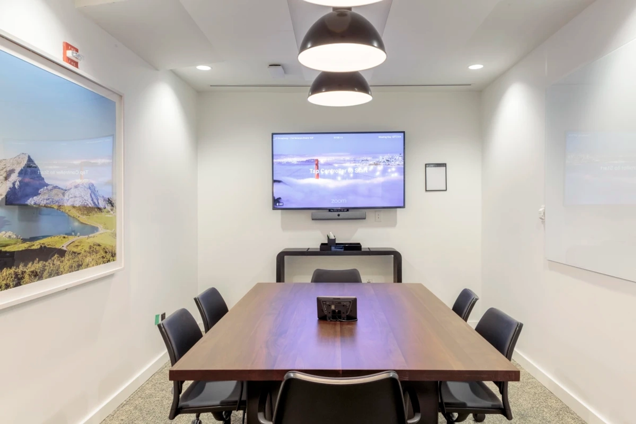 A coworking space with a conference room equipped with a TV on the wall.