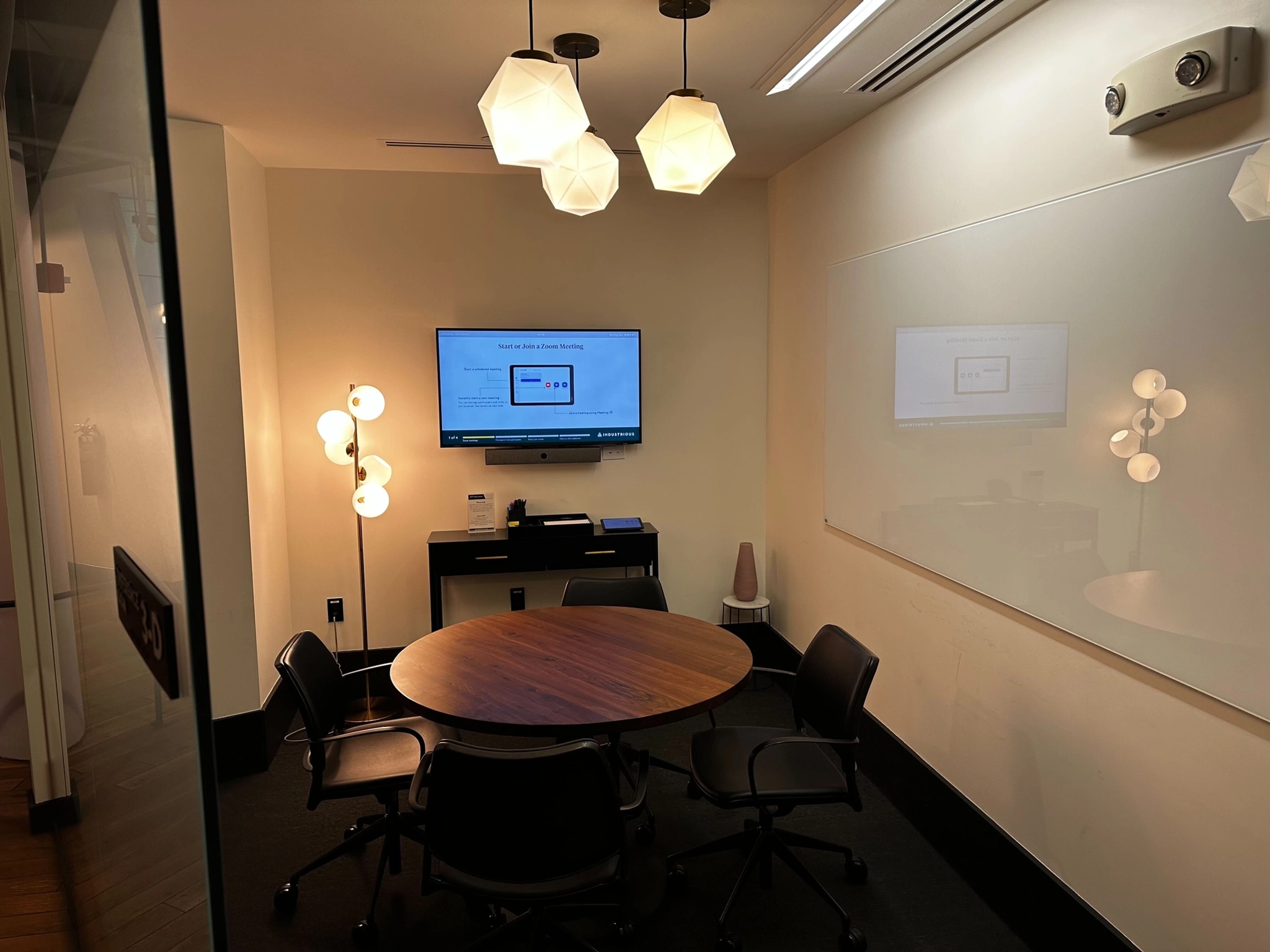 Un bureau salle de conférence avec table et chaises pour le coworking et les réunions, équipé d'une télévision.