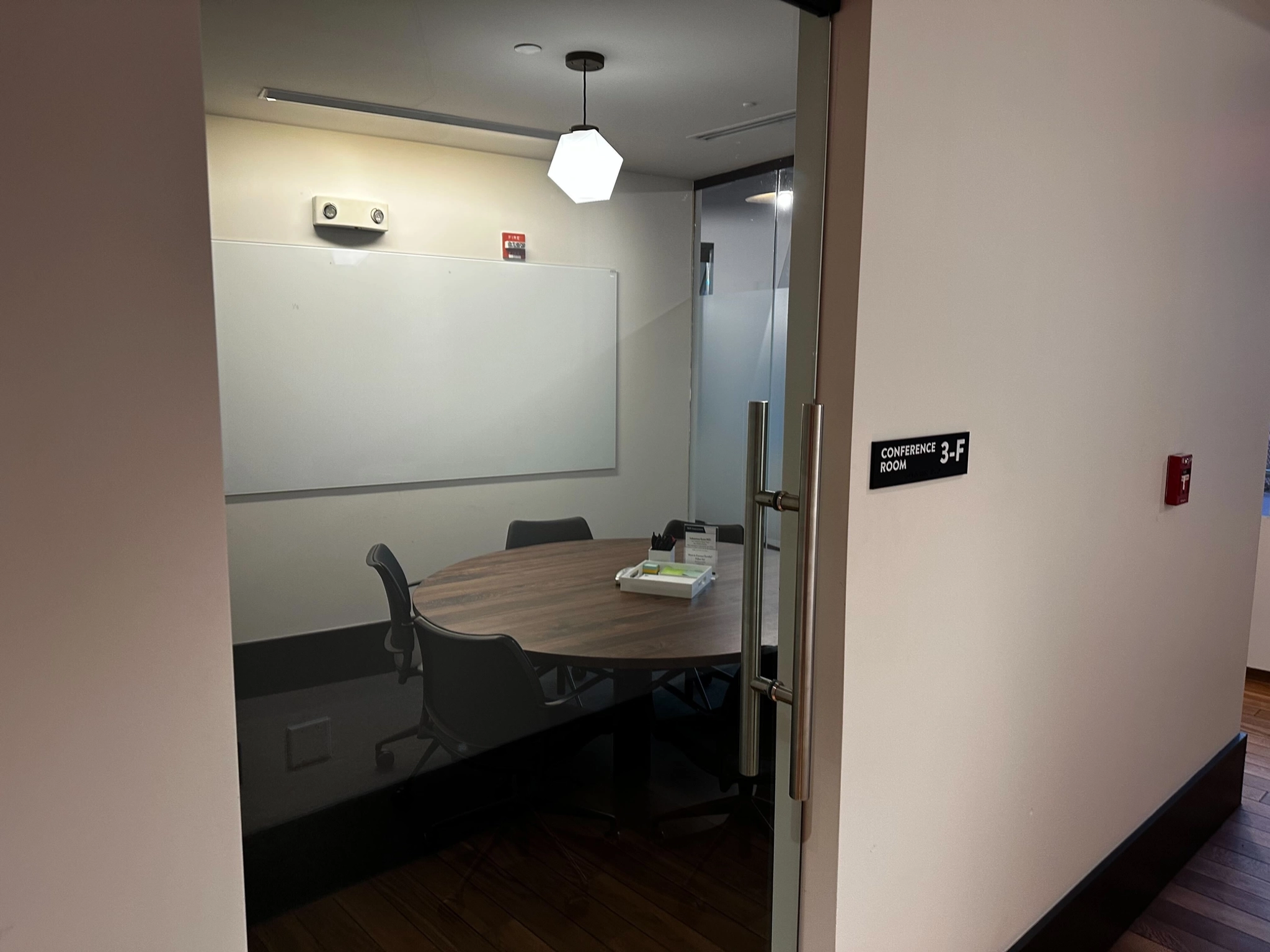 A coworking meeting room in New York with a glass door and a white board.