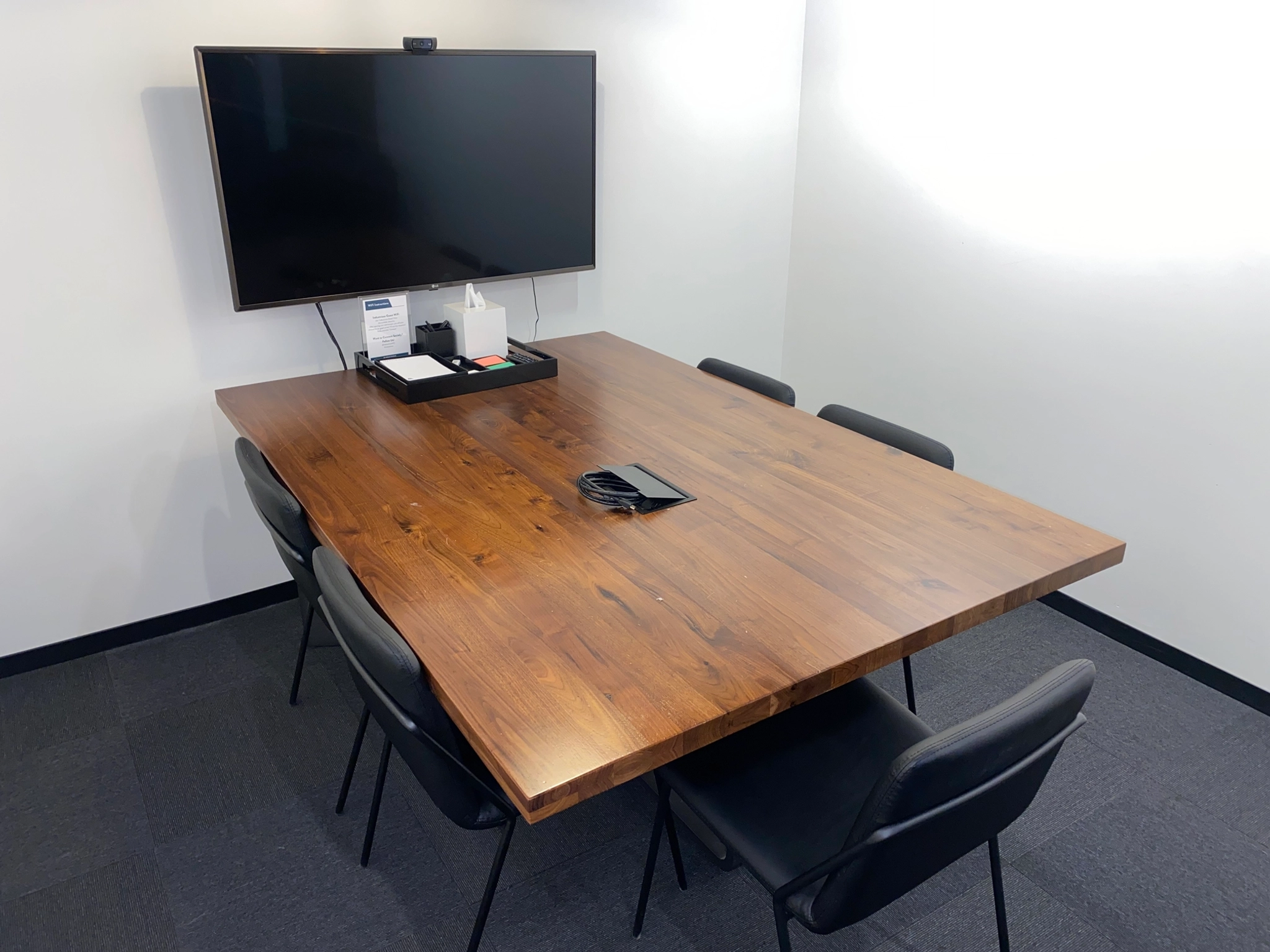 Een coworking-ruimte in Boston met een houten tafel en een televisie.