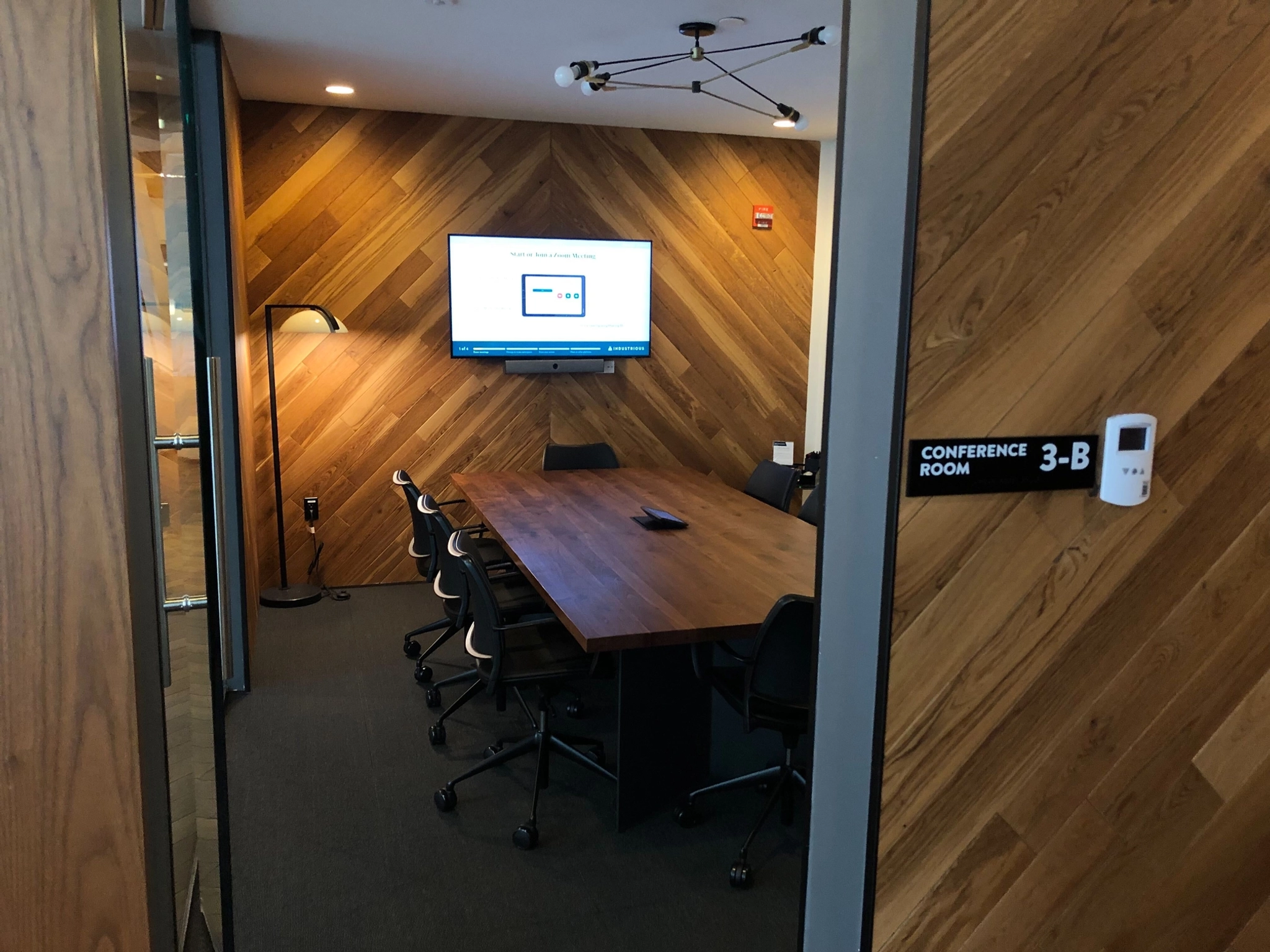 Une salle de réunion de bureau à New York avec des murs en bois et une télévision.