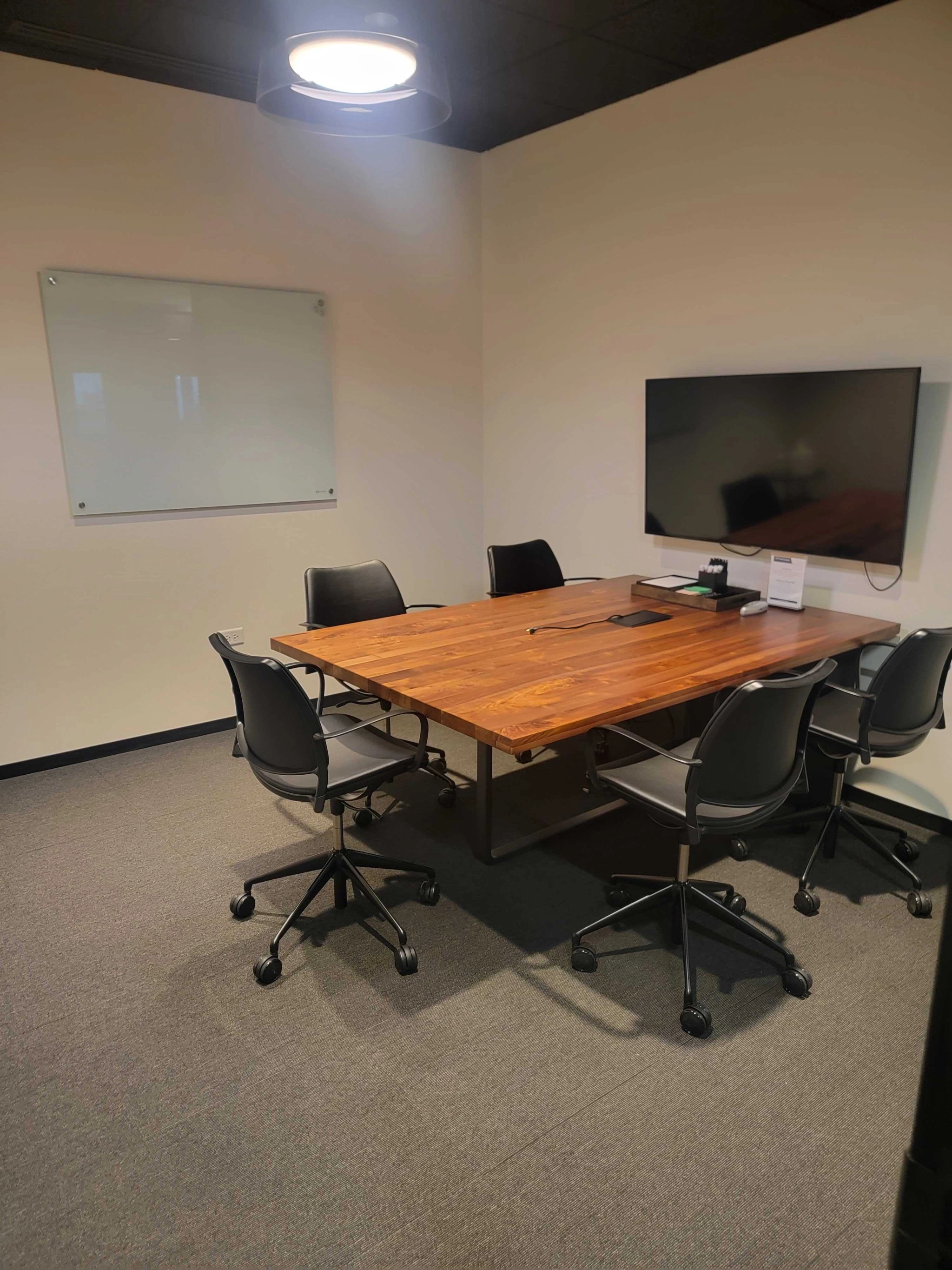 Een vergaderruimte in Chicago met een houten tafel en stoelen, perfect voor coworking.