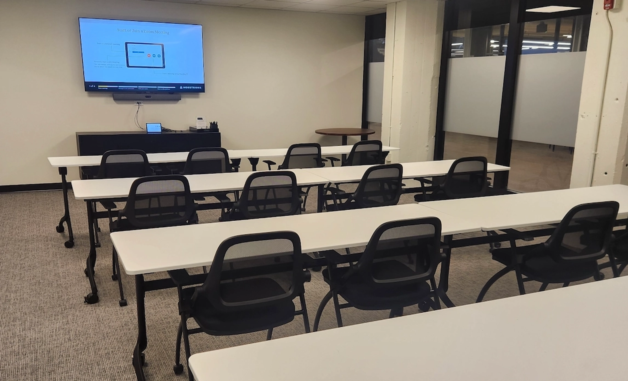 Modern meeting room with a presentation screen and empty chairs.