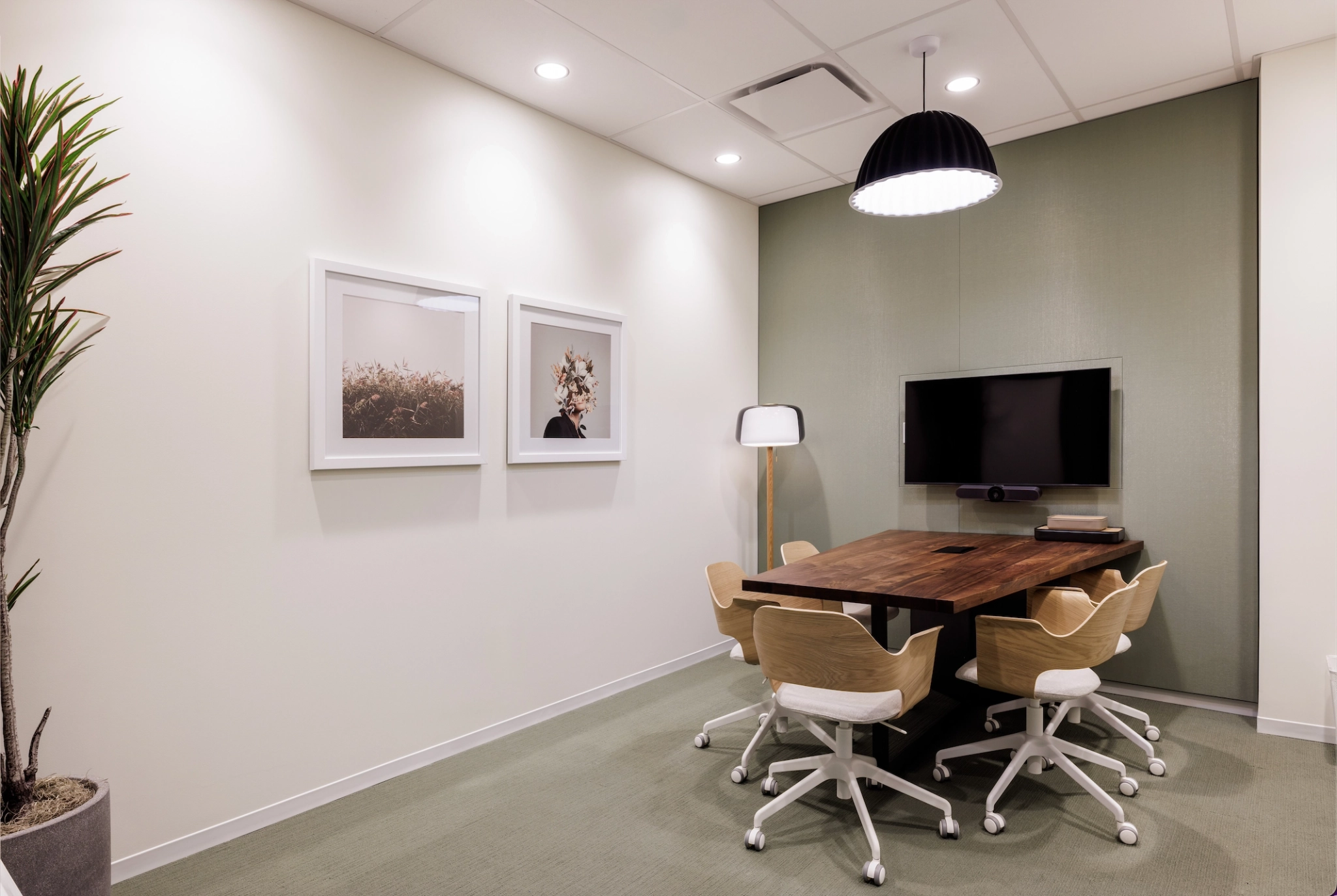 A meeting room with a table, chairs, and a TV for coworking.