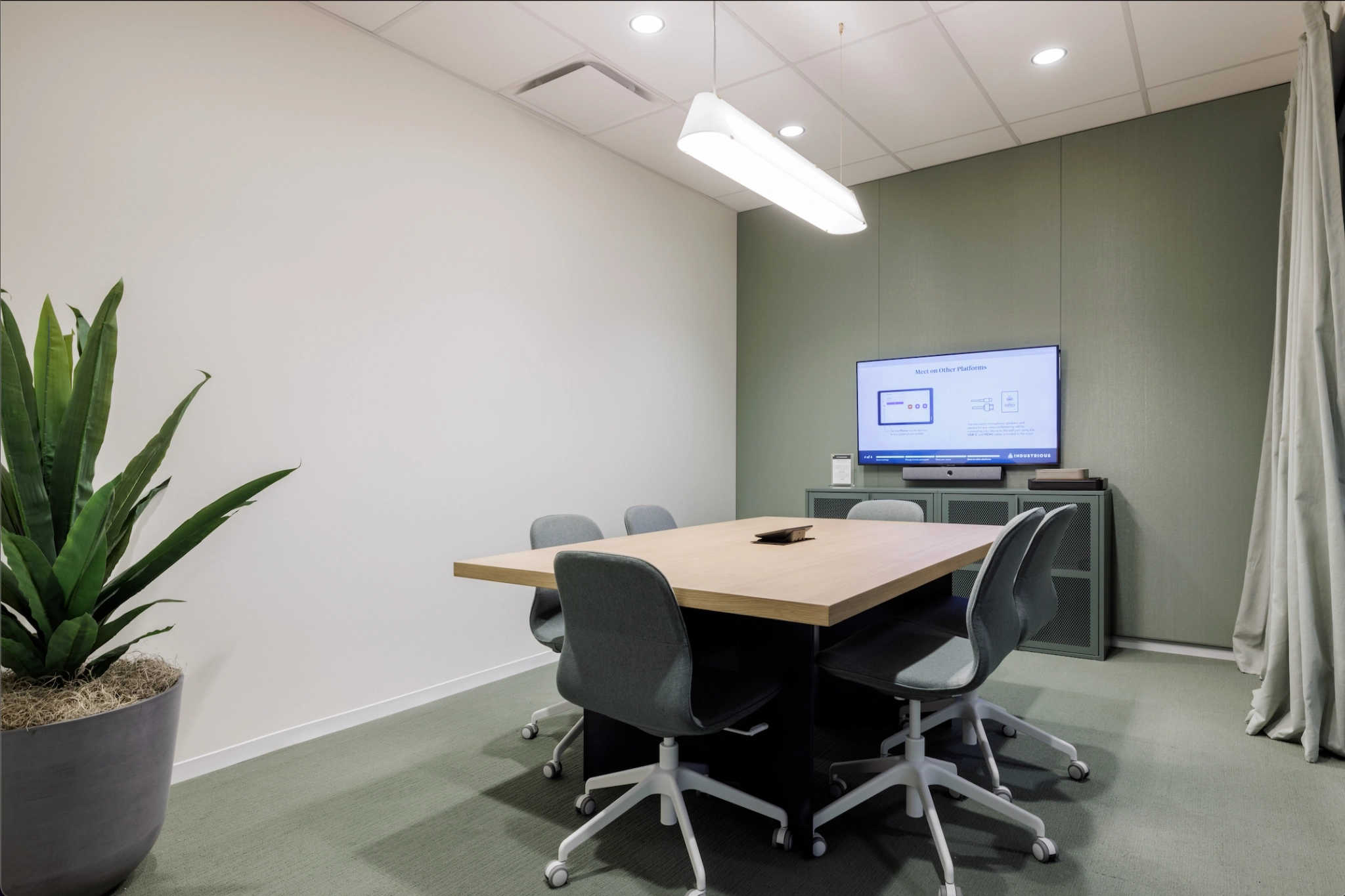 Un bureau salle de réunion avec une table, des chaises et une plante.