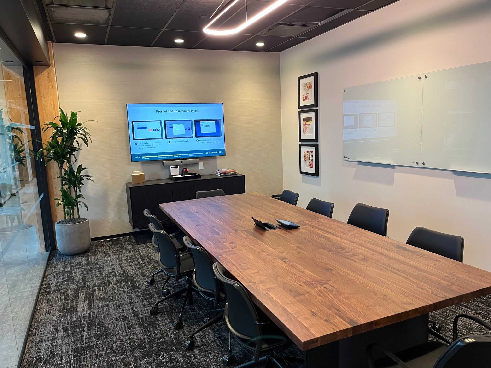 Moderne coworking-conferentieruimte in Brooklyn met een grote houten tafel, bureaustoelen, presentatiescherm en whiteboards.