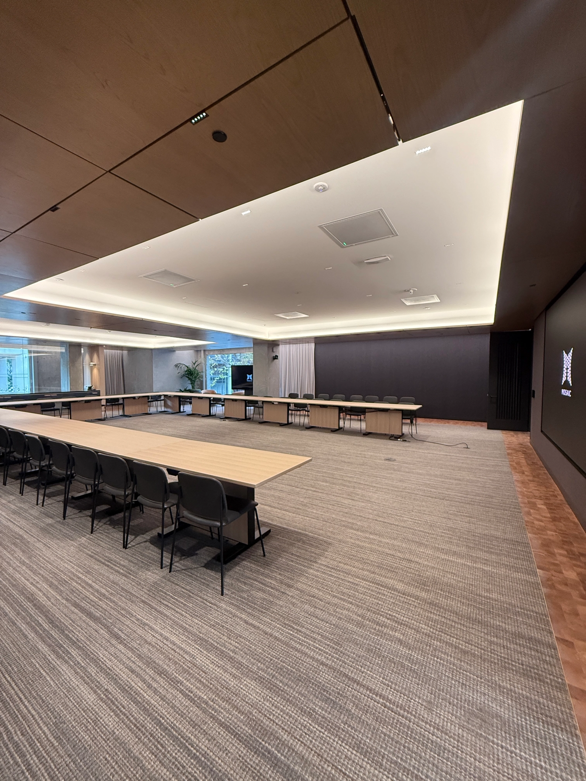 A large, modern conference room in a San Francisco coworking space features a long table, black chairs, wood-paneled walls, and a carpeted floor.